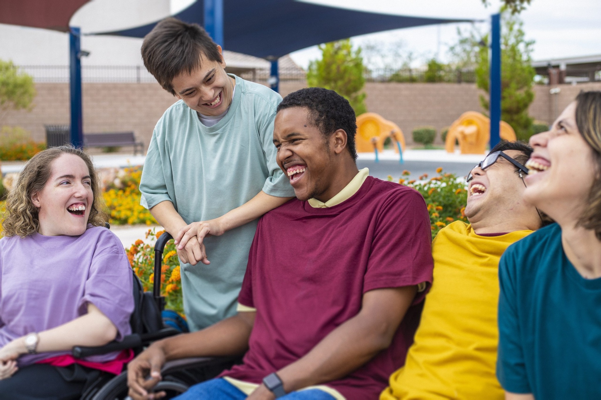 Five adults laughing together outdoors